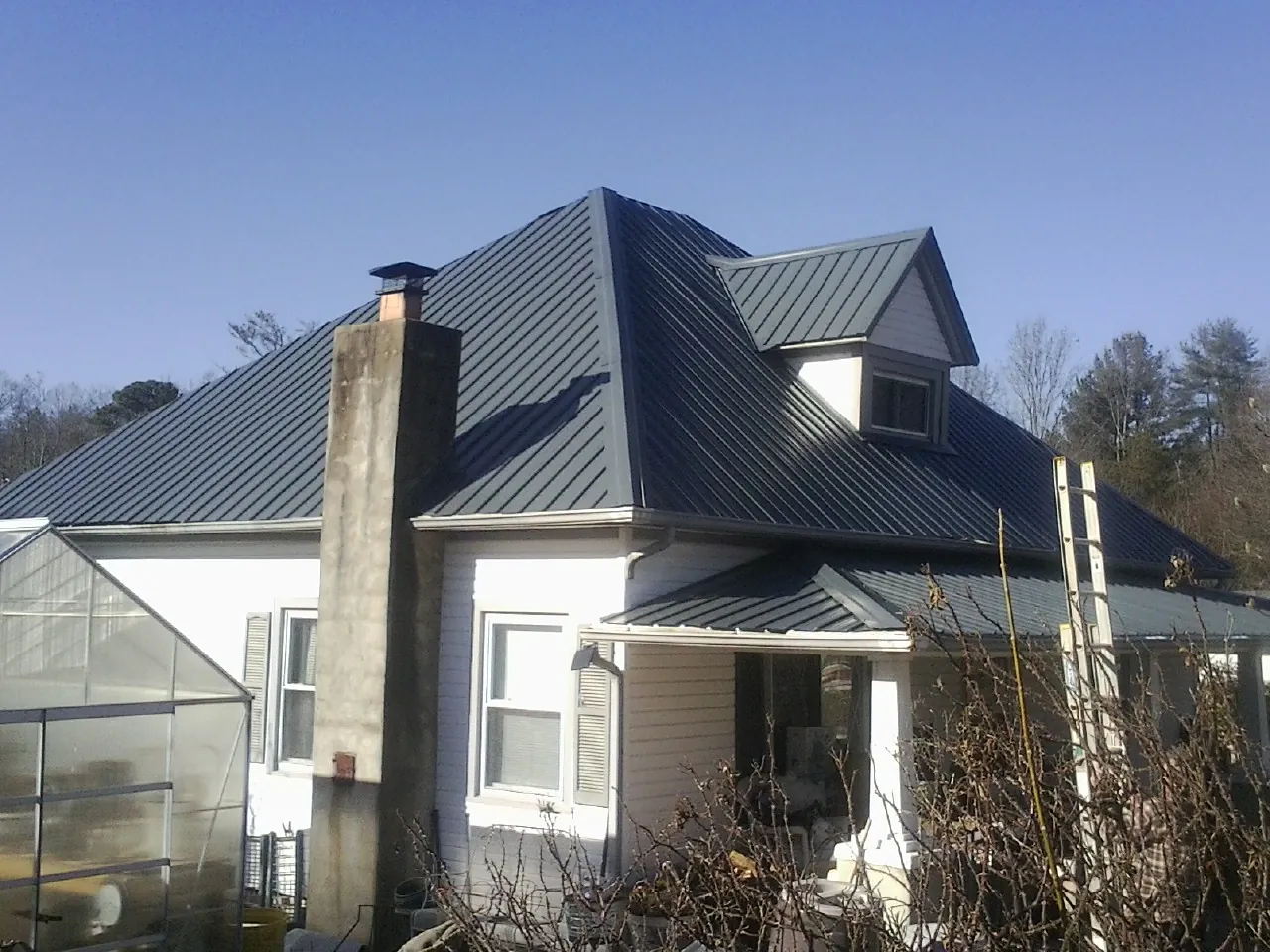 Dark blue standing seam metal roof on a white farmhouse with dormer — Slate & Tile Roof Repair by Roofing Brothers in South Lyme