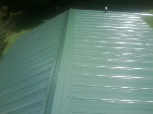 New green metal panels meeting at the ridge of a roof — Flat Roof Repair work by our crew in South Lyme