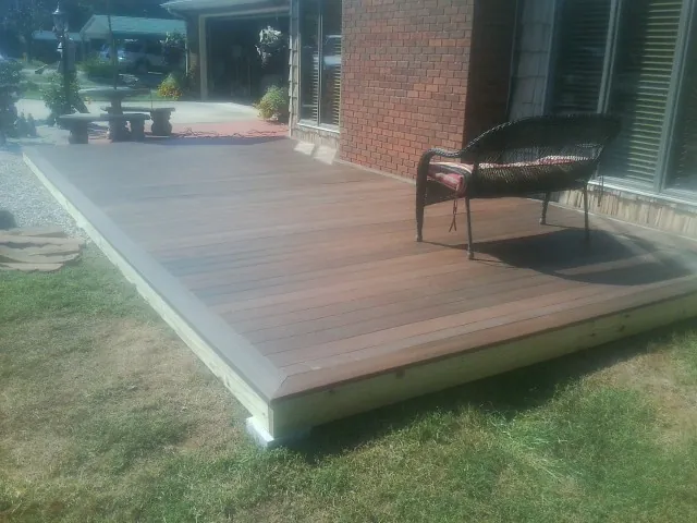 New wood deck and wicker chair beside a brick house in South Lyme