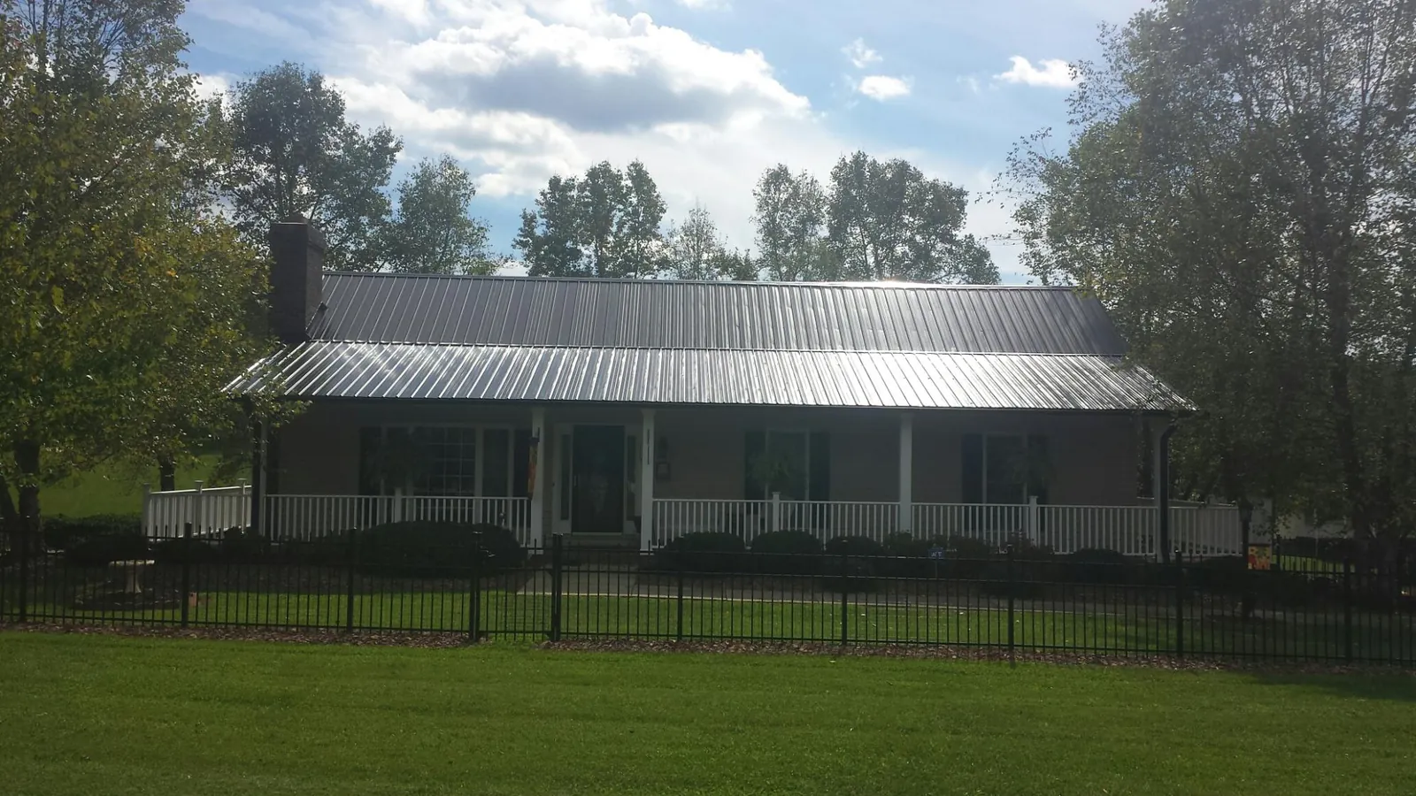 Gray metal roof on a brick ranch with a full width front porch — Gutter Guard Installation work by our crew in South Lyme