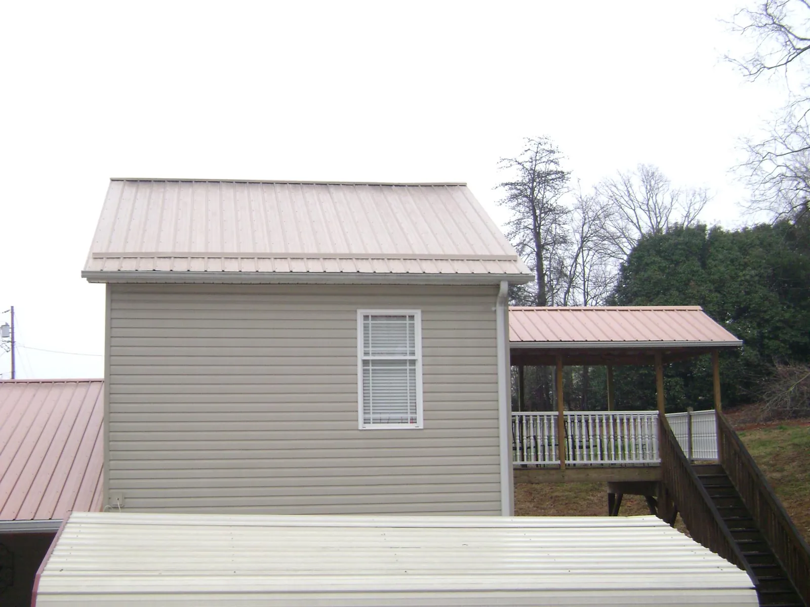 Tan metal roofs on a two story addition and attached porch, from a Roof Replacement job in South Lyme