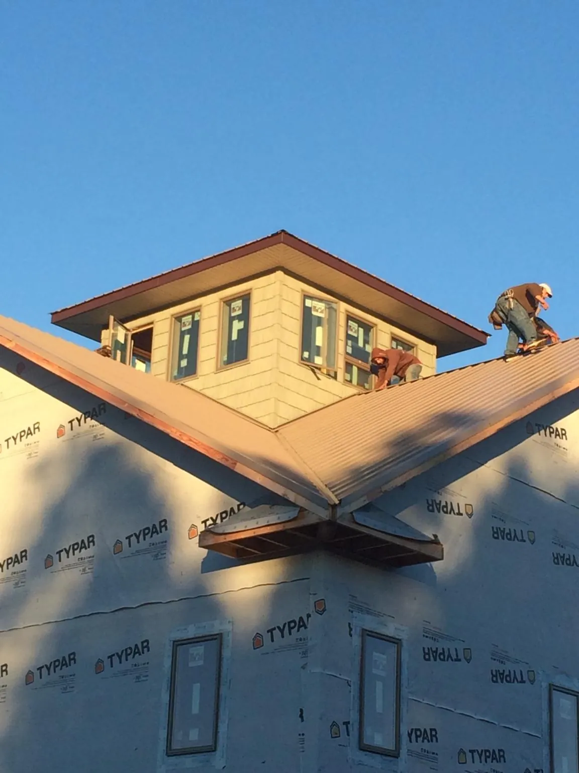 Roofers working around a rooftop cupola on a new metal roof at sunset — Roof Waterproofing in South Lyme by Roofing Brothers